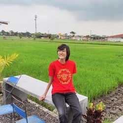 Portrait of young woman standing on field against sky