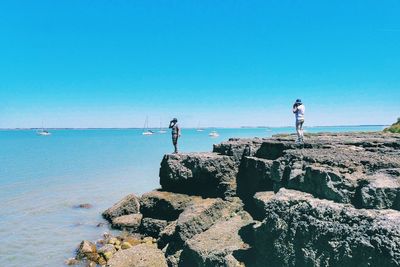 People standing at beach against blue sky