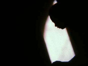 Close-up portrait of silhouette man standing against black background