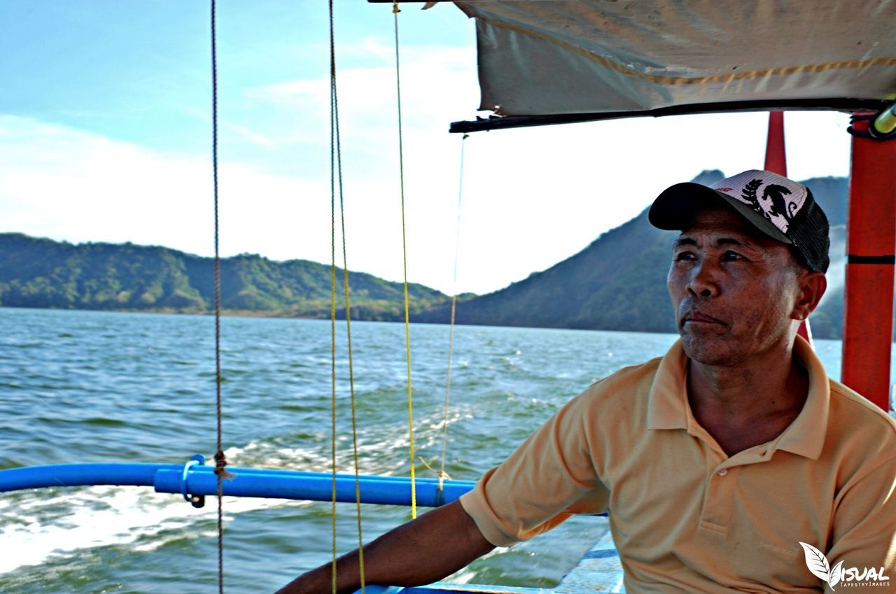 water, mountain, sky, nautical vessel, sea, blue, mountain range, lake, young adult, nature, sitting, day, boat, leisure activity, one animal, lifestyles, portrait, beauty in nature