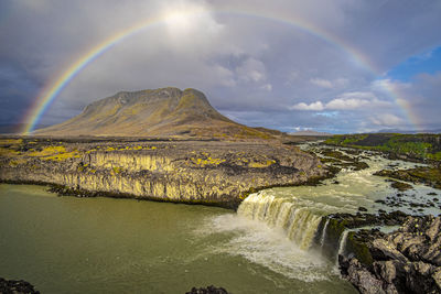 Scenic view of rainbow over river against sky