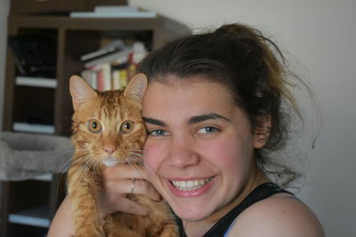 Portrait of smiling young woman with cat at home