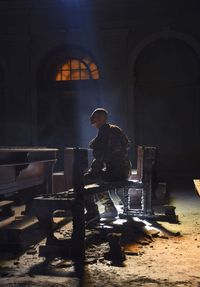 Man sitting on bench in abandoned darkroom