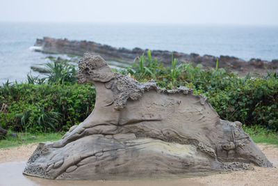 Statue by sea against sky