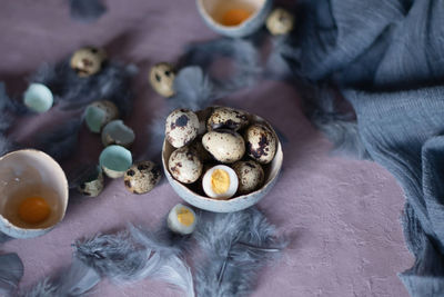 Quail eggs in ceramic vases, gray feathers on the table, easter still life,