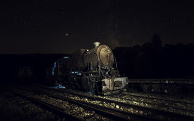 Train on railroad tracks against sky at night