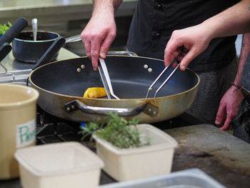 Chef cooking and grilling onions and a golden potato on a pan in a professional restaurant kitchen. 