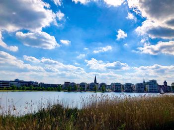 Scenic view of river by buildings in city against sky