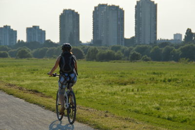 Rear view of man riding bicycle on city