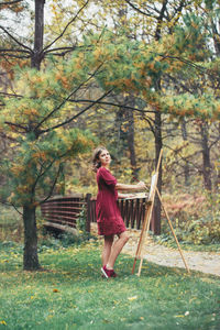 Side view full length portrait of woman painting at park