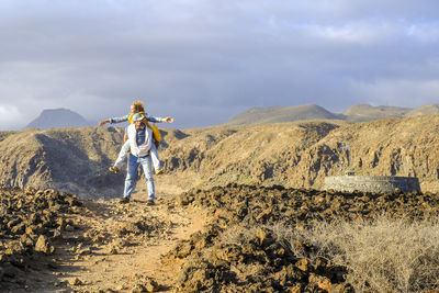 Rear view of man walking on mountain against sky