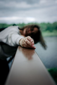 Defocused image of woman relaxing on railing against sky