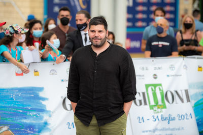 Full length portrait of young man standing against people