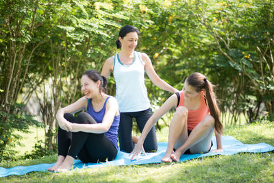 Yoga instructor instructing to women doing yoga at park