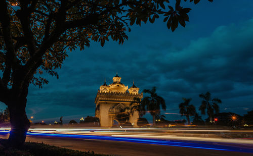 Light trails on the road against cloudy sky