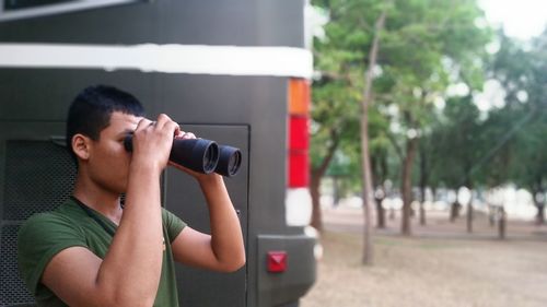 Man looking through binoculars by bus