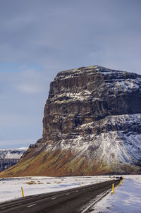 Road by snowcapped mountain against sky