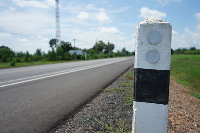 Road sign on roadside against sky