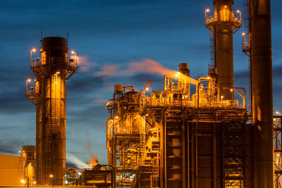 Illuminated factory against sky at night