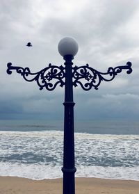 Street light on beach against sky