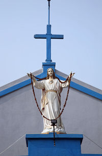 Low angle view of jesus christ statue by church against sky