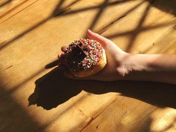 High angle view of hand holding fresh donut on table