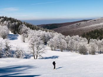 Woman on snow covered field against sky