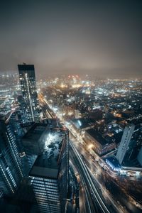 High angle view of illuminated street amidst buildings in city at night