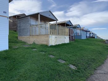 Barn on field by buildings against sky