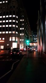 Illuminated street amidst buildings in city at night