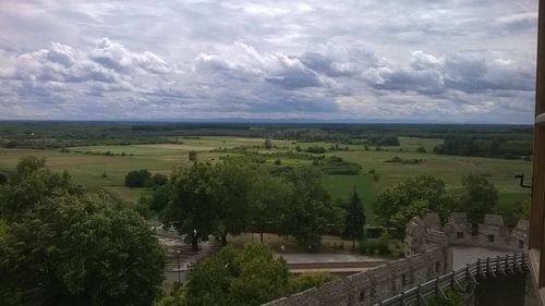 Trees on landscape against cloudy sky