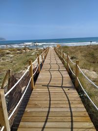Boardwalk leading towards beach against sky