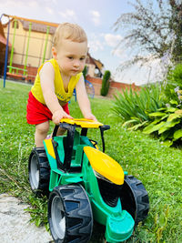 A little cute boy of one and a half years plays with toy tractor outdoor. adorable toddler playing 