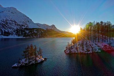 Scenic view of lake and mountains against sky at sunset