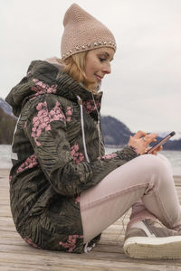 Side view of woman using mobile phone on pier