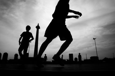 Low angle view of silhouette people in city against sky