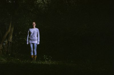 Full length portrait of smiling woman standing in forest