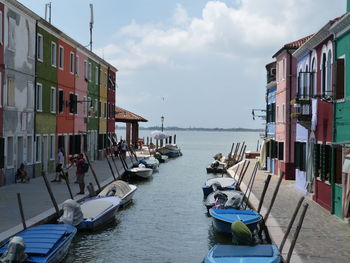 Boats moored on sea by buildings against sky