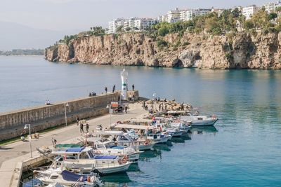 Antalya, turkey - november 15, 2022. small fishing boats at the harbor with a lighthouse.