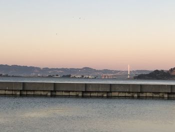 Bridge over sea against sky during sunset