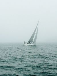 Sailboat sailing in sea against sky during foggy weather