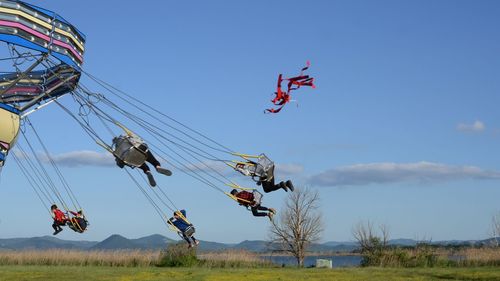 Low angle view of people in amusement park ride against sky