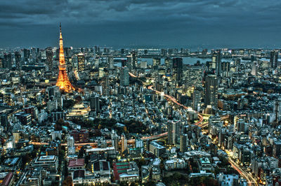 Tokyo tower amidst cityscape against sky at dusk