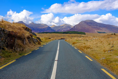 Road leading towards mountains against sky