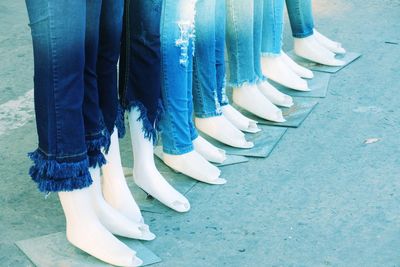 Low section of mannequins wearing various jeans pants outdoors