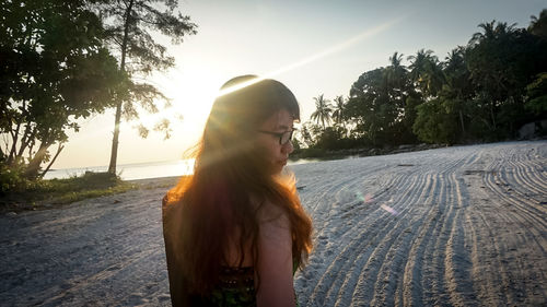 Young woman standing on road against trees