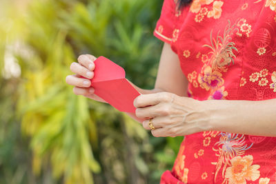 Midsection of woman holding red envelope