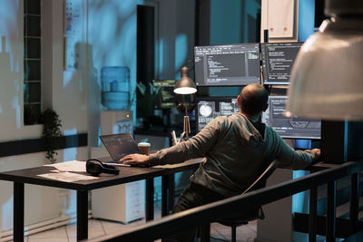 Rear view of man using laptop at office