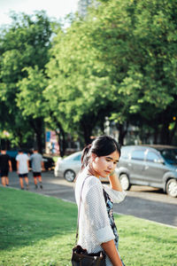 Woman standing on grass against trees