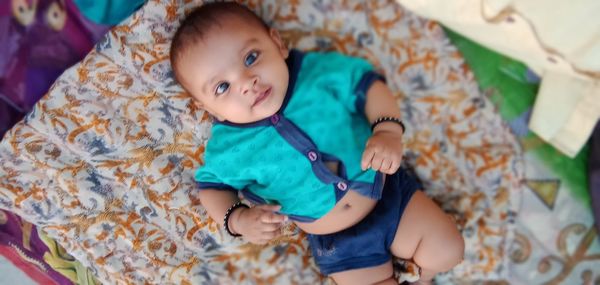 High angle portrait of cute baby lying on bed